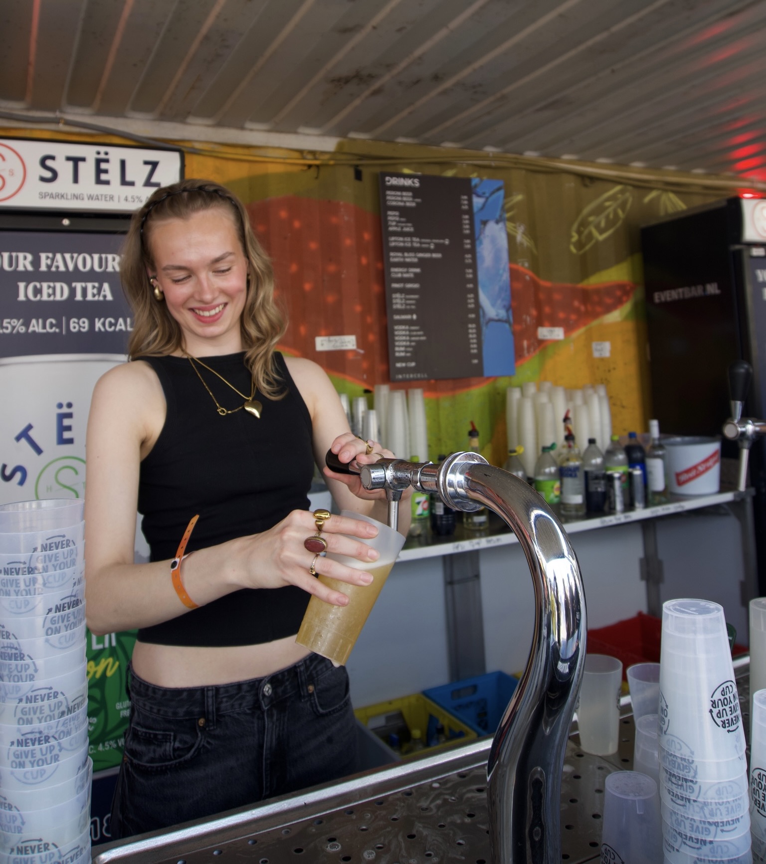 Vrolijke Crewmate tapt bier met een grote glimlach op een kleurrijk festival